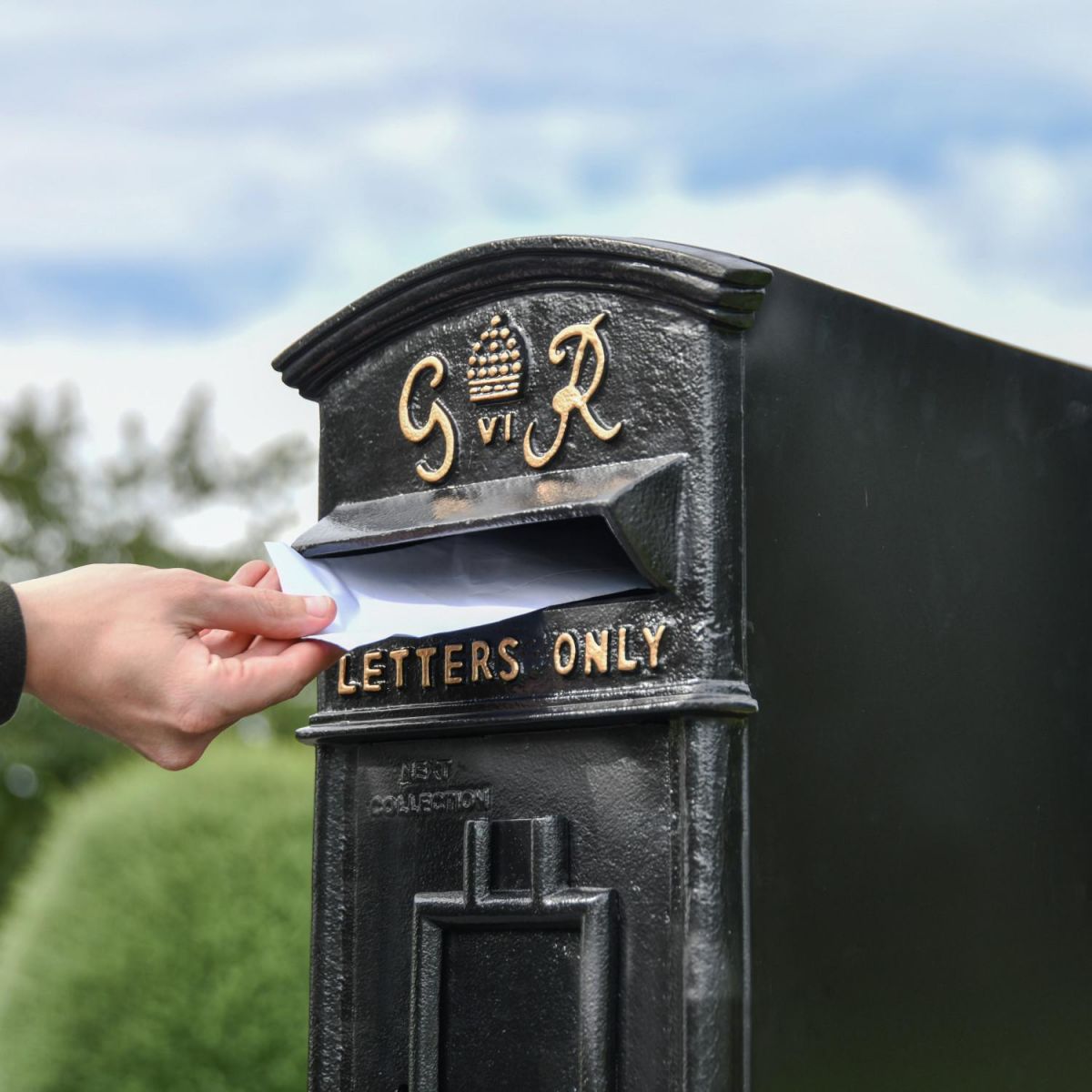 Close-Up of Letter Opening in Use on Freestanding Black Post Box