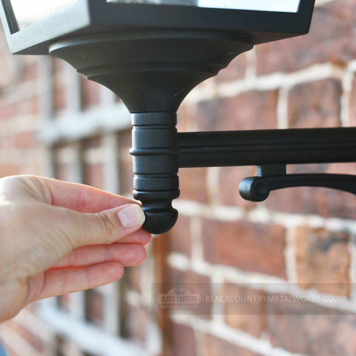 Black outdoor traditional wall lamp close up of bracket attachment