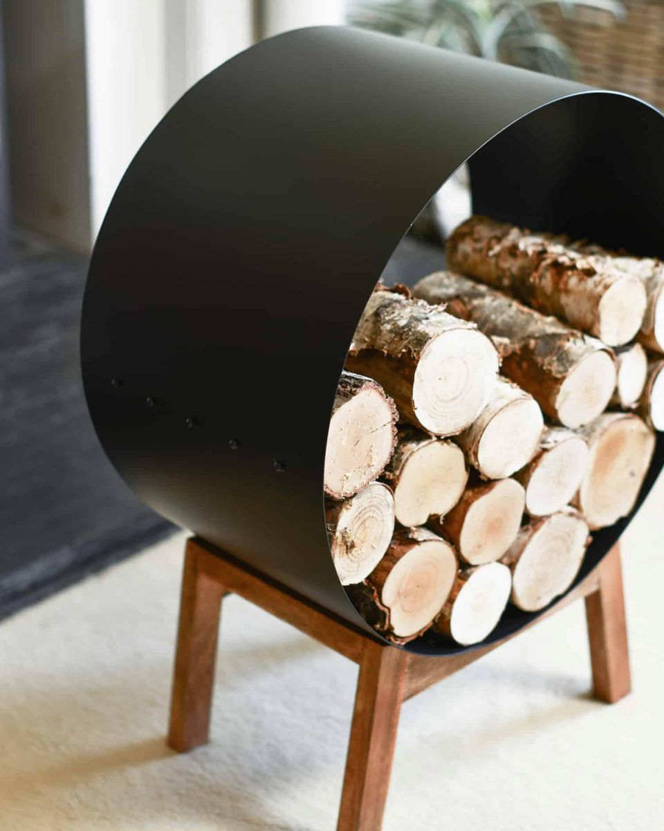 Close-Up of Black Round Steel "Barrel" Log Holder with Wooden Legs in Situ Close-Up of Black Round Steel "Barrel" Log Holder with Wooden Legs in Situ