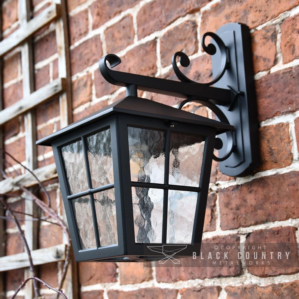 Black Traditional Top Fix Wall Lantern with Ornate Bracket in Situ on a Brick Wall