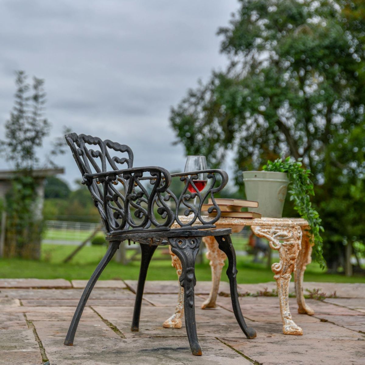 Side view of Aged Black Heart Scrolled Garden Chair in Garden Side view of Aged Black Heart Scrolled Garden Chair in Garden