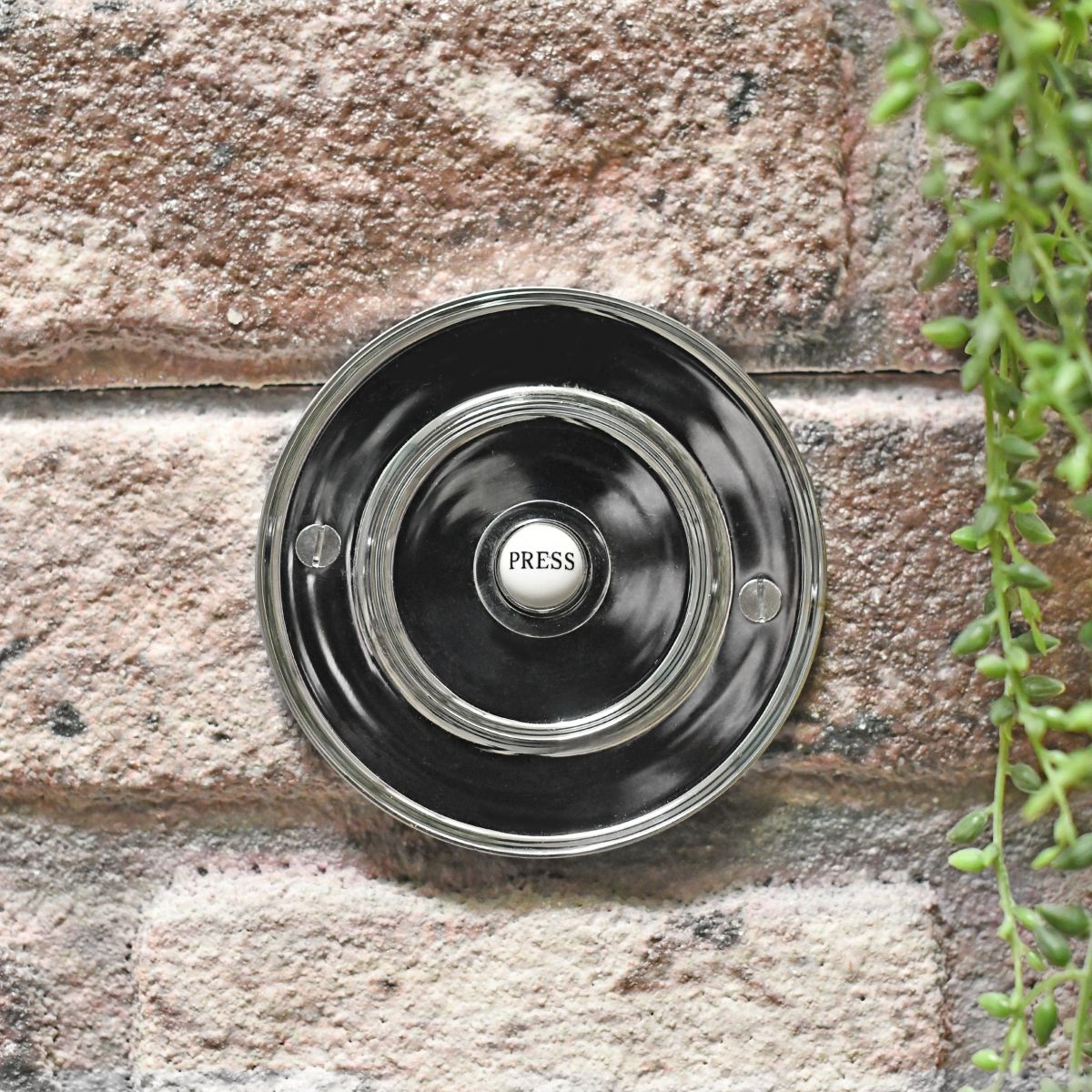 Circular chrome door bell on brick wall