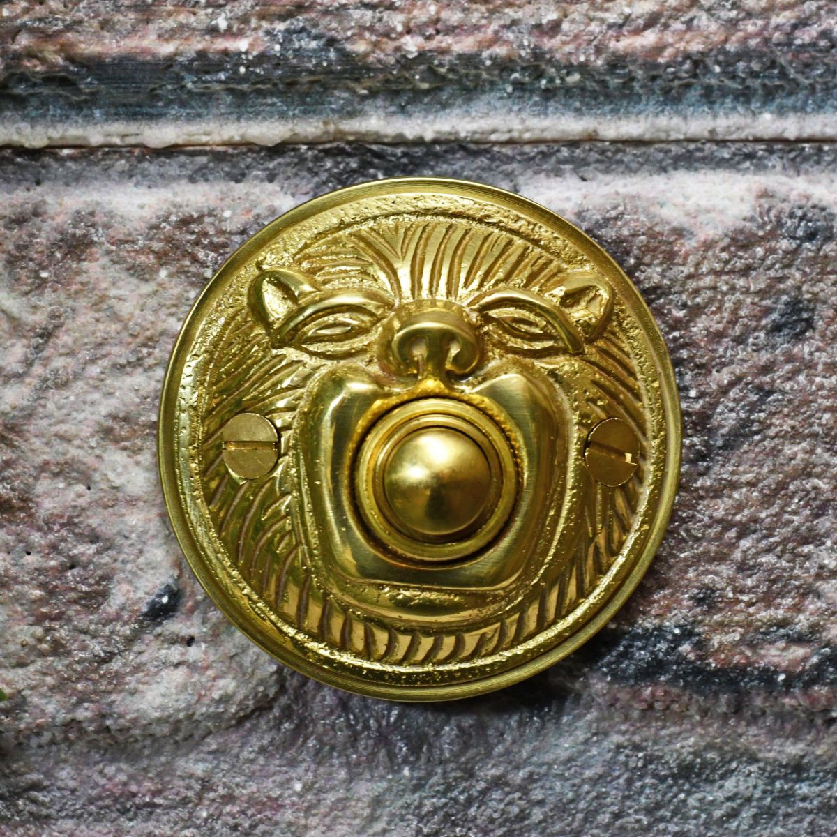 Polished brass bell push on brick wall 