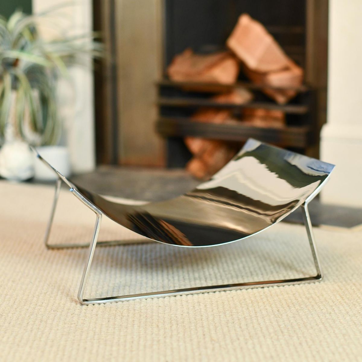 Bright Chrome Curved Contemporary Log Holder in situ by the Fireplace Bright Chrome Curved Contemporary Log Holder in situ by the Fireplace