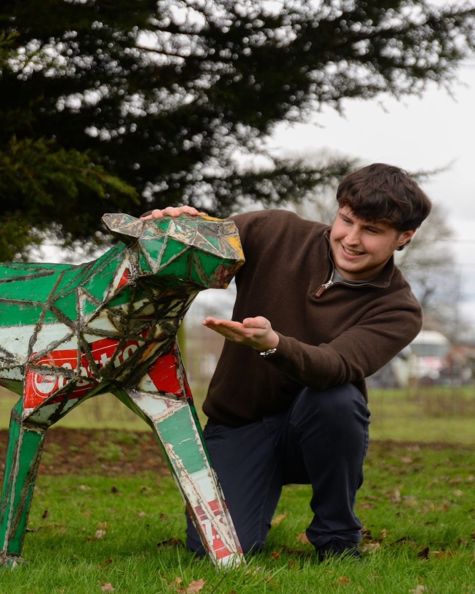 "Diesel" the Cheetah Upcycled Oil Drum Garden Sculpture to scale with man crouching next to sculpture