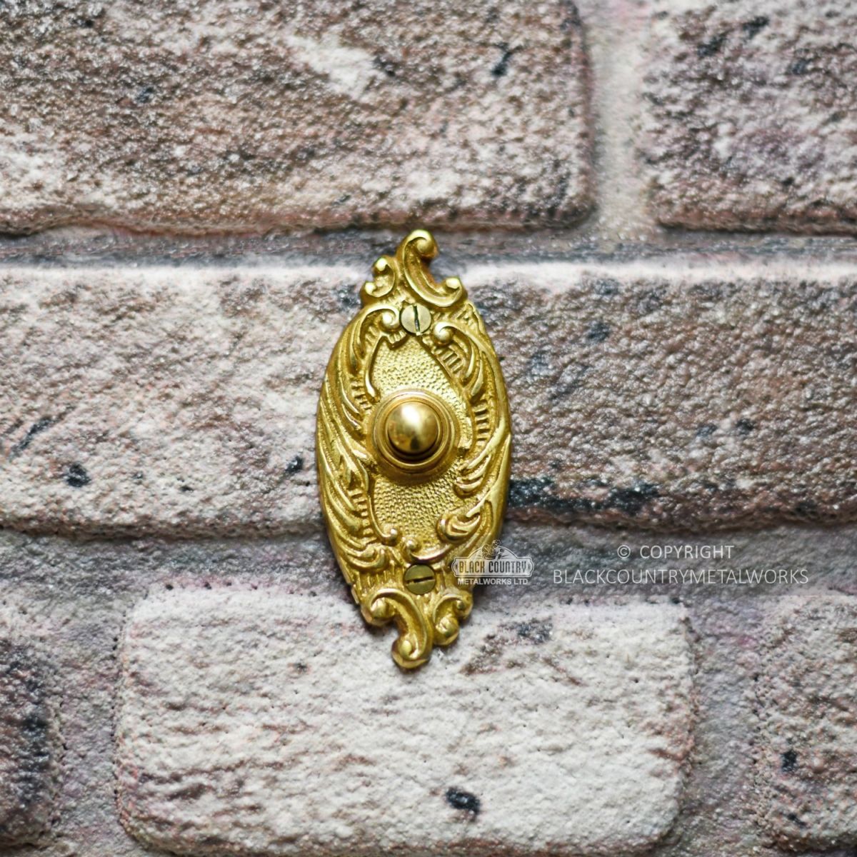 Clarice Oval Polished Brass Ornate Bell Push Installed On Brick Wall Clarice Oval Polished Brass Ornate Bell Push Installed On Brick Wall