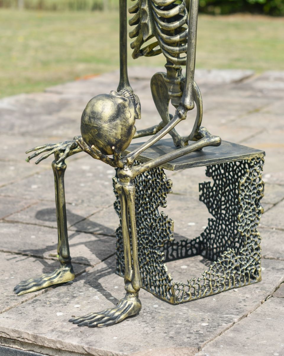 Close up of skeleton holding skull with freestanding base outdoor statue