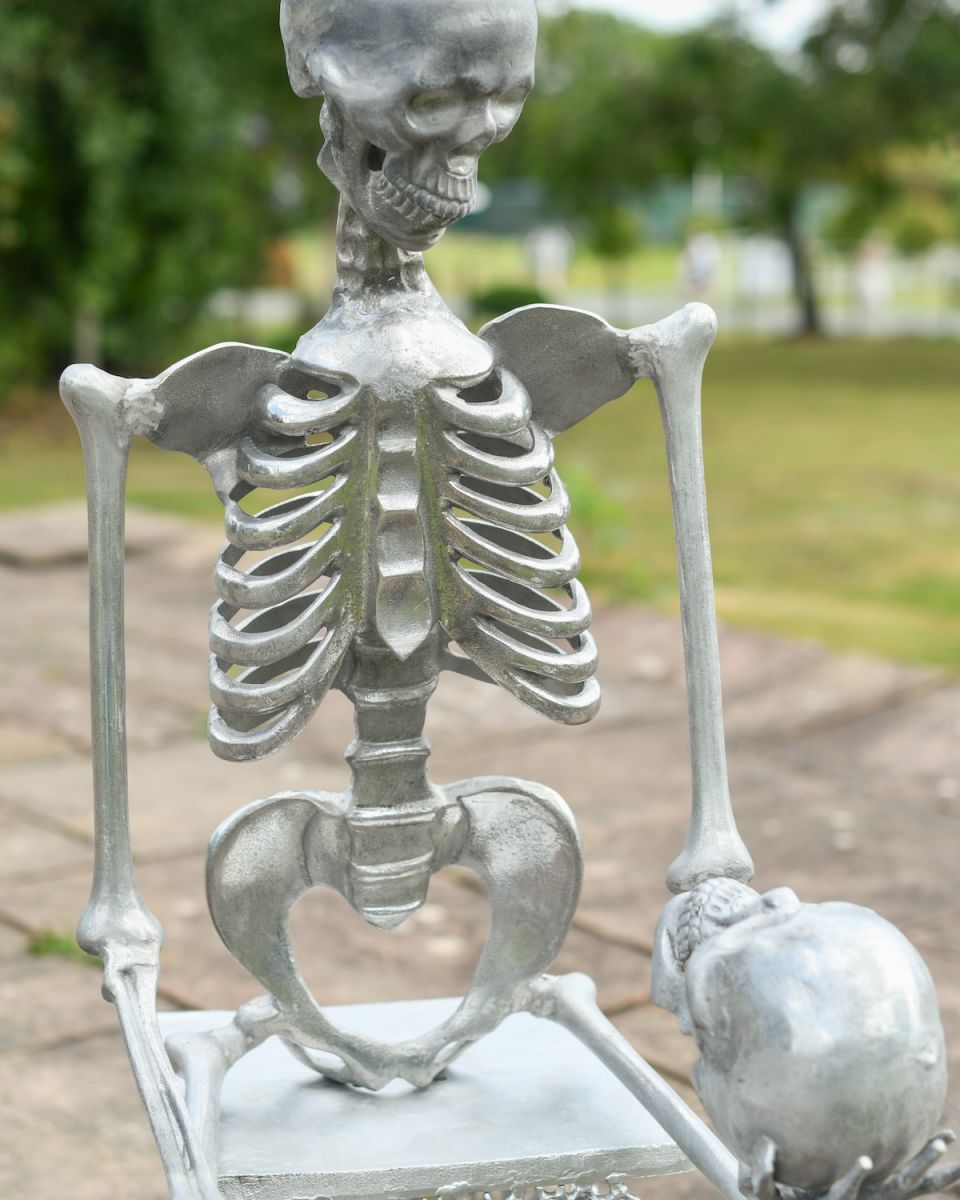 Close up of intricate detail on skeleton holding skull garden sculpture