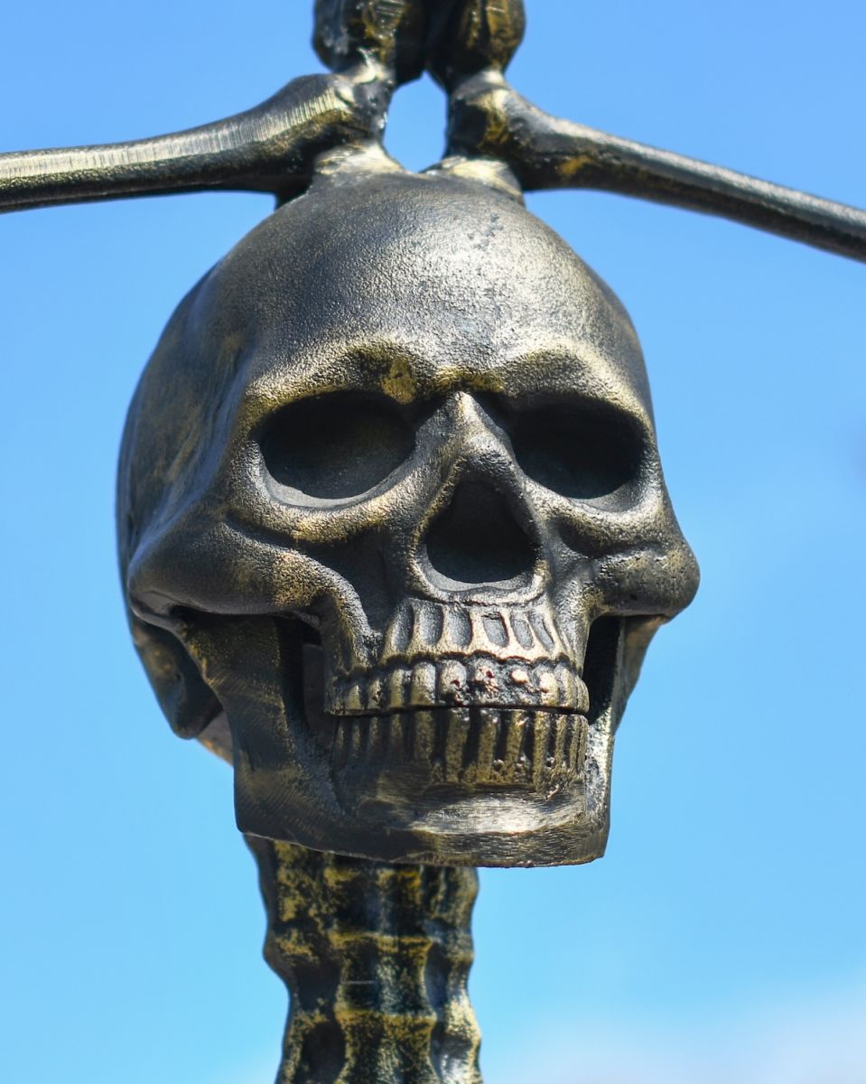 Close up of intricate brushed gold skull on skeleton garden statue
