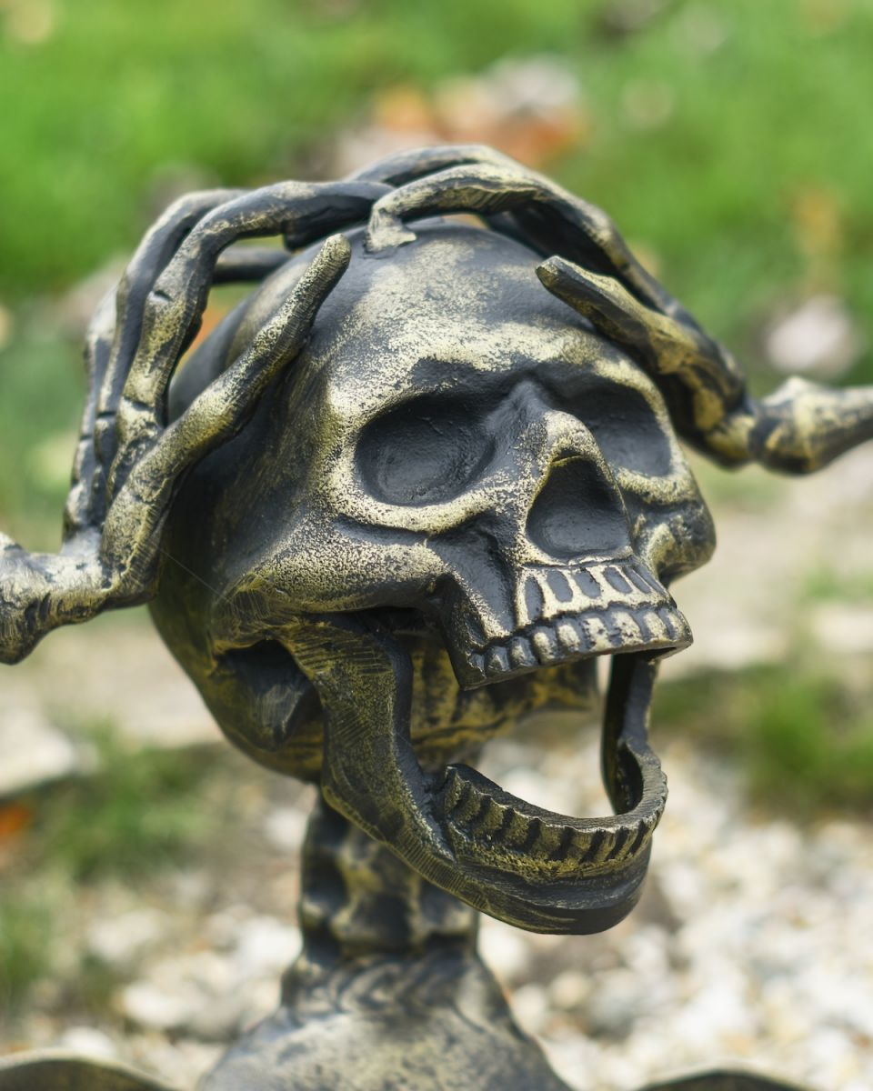 Close up of intricate face detail on half skeleton garden ornament