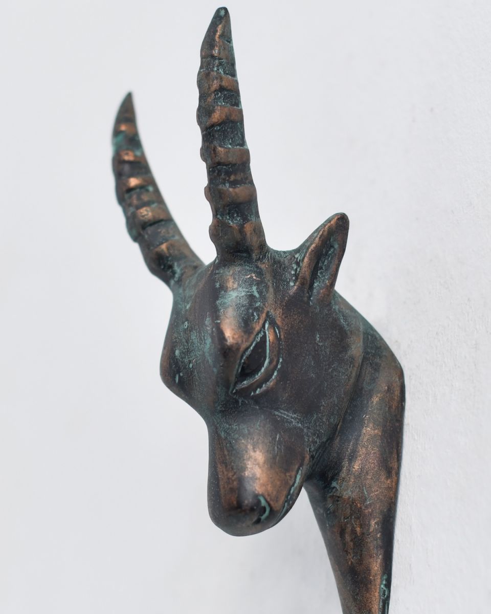 Close up of intricate gazelle head detail on verdigris coat hook