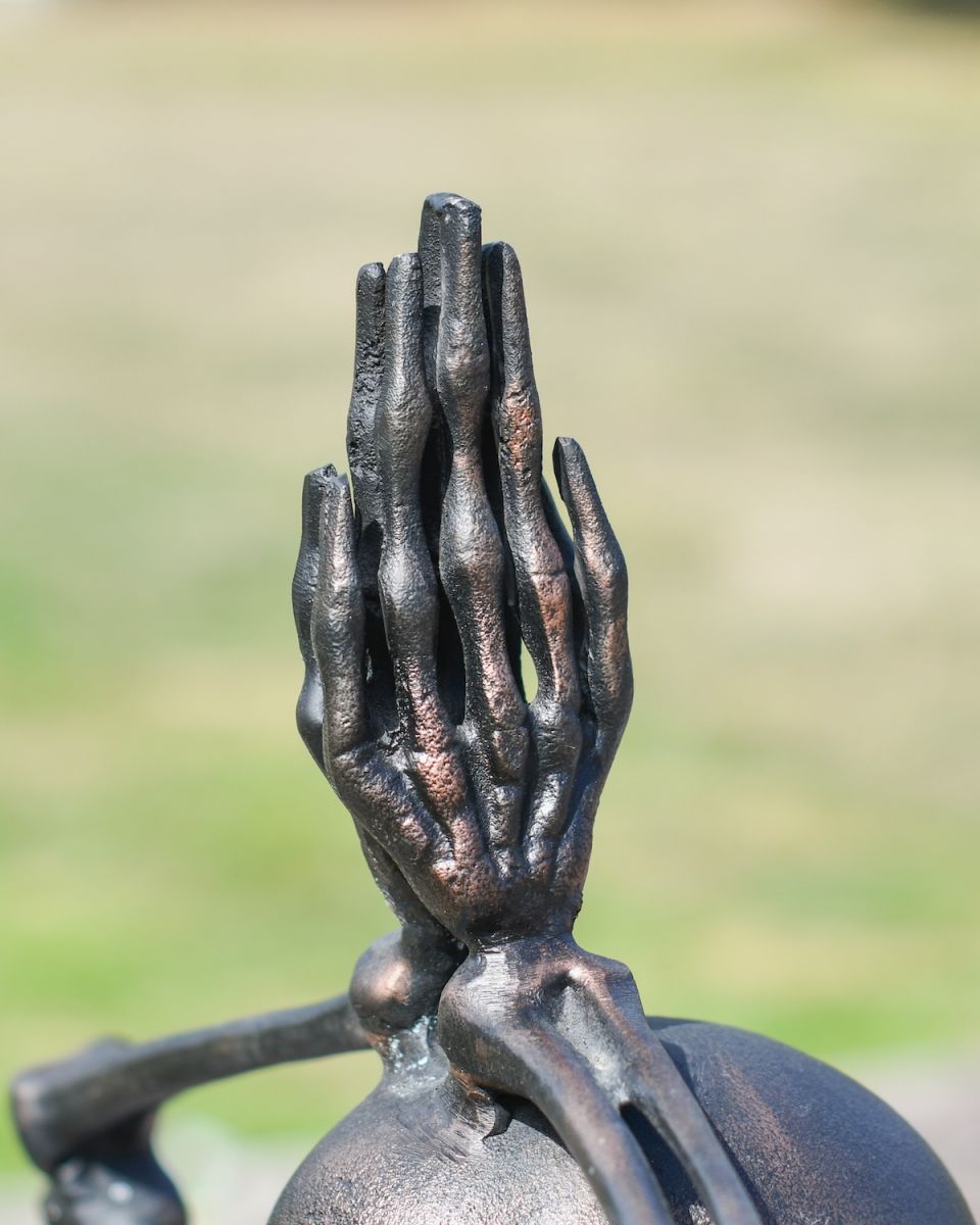 Close up of intricate skeleton hands detail on brushed copper garden statue