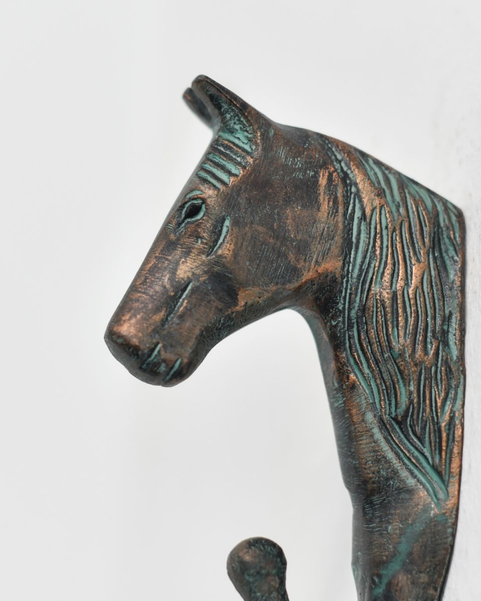 Close up of intricate horse head detail on verdigris coat hook