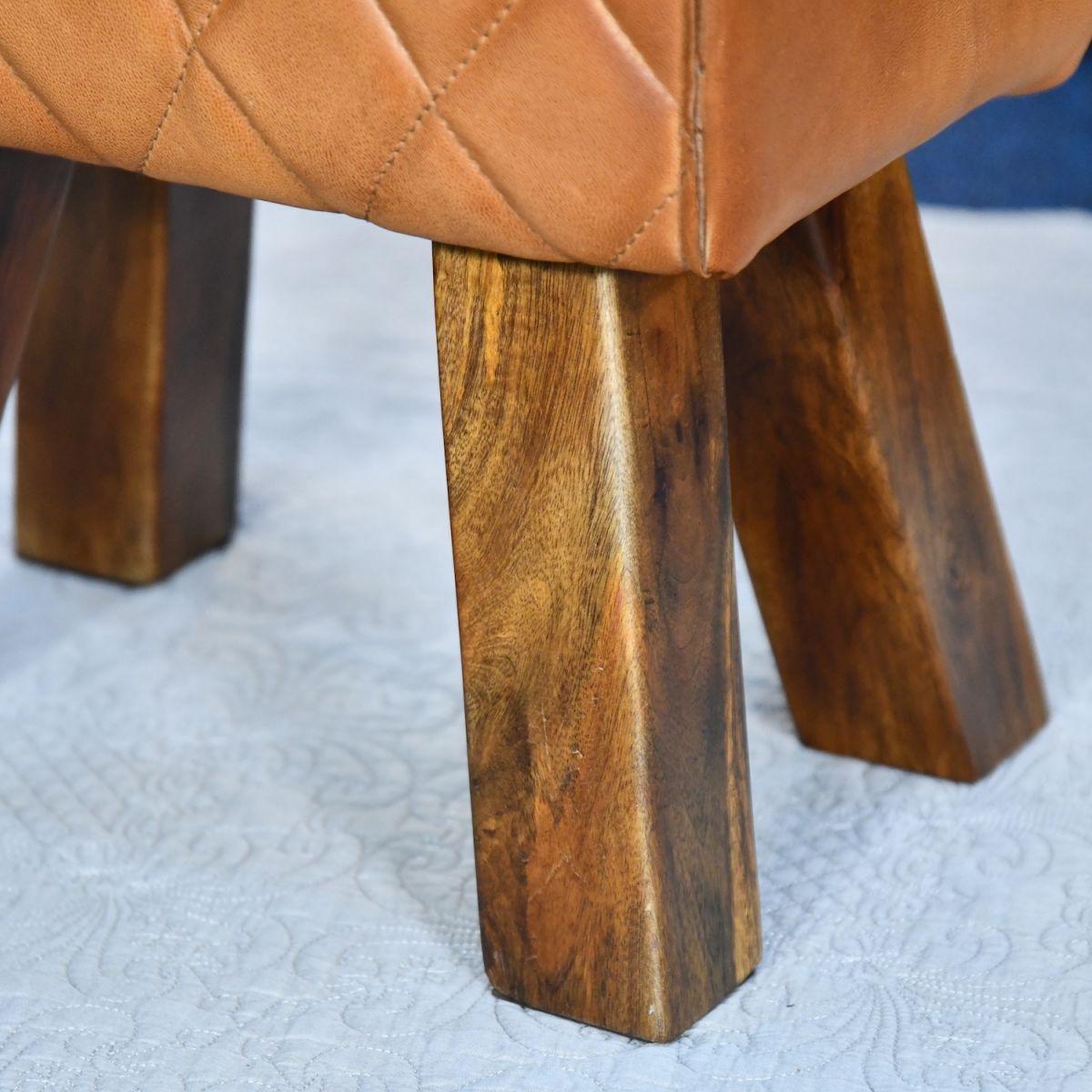 Close up of mango wood legs on genuine leather tan foot stool