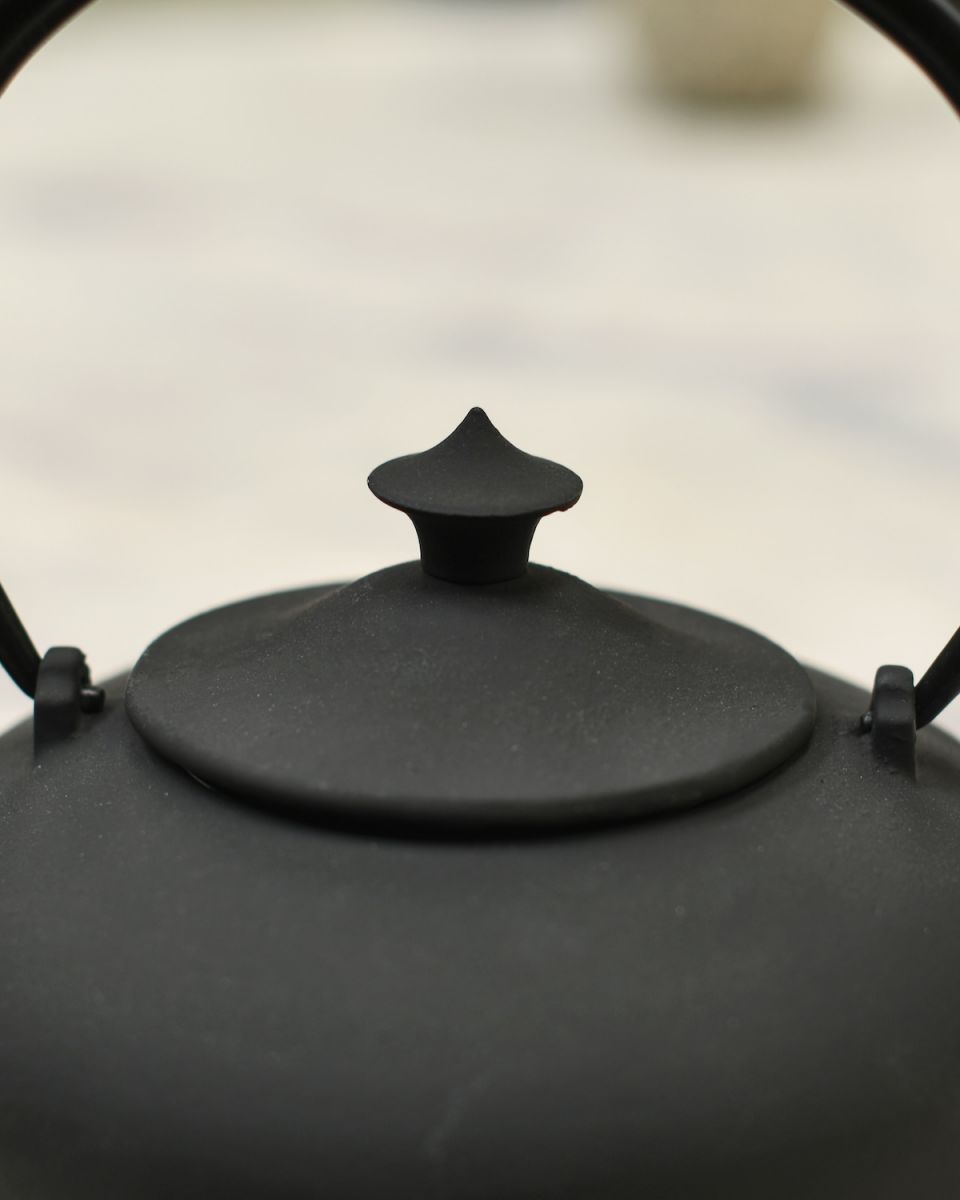 Close up of ornate lid detail on matte black teapot Close up of ornate lid detail on matte black teapot