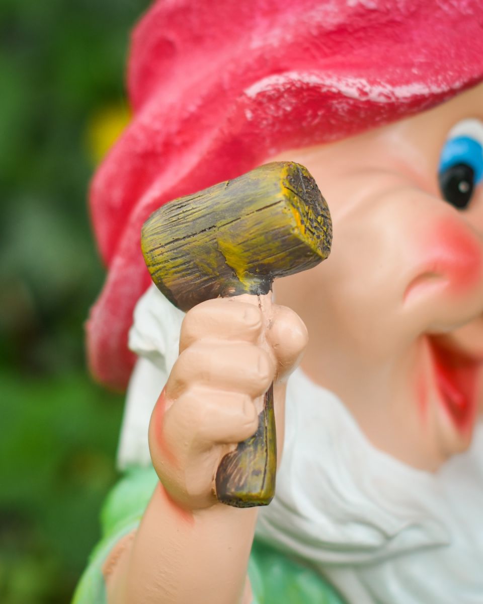 Close up of wooden mallet detail on colourful outdoor gnome sculpture