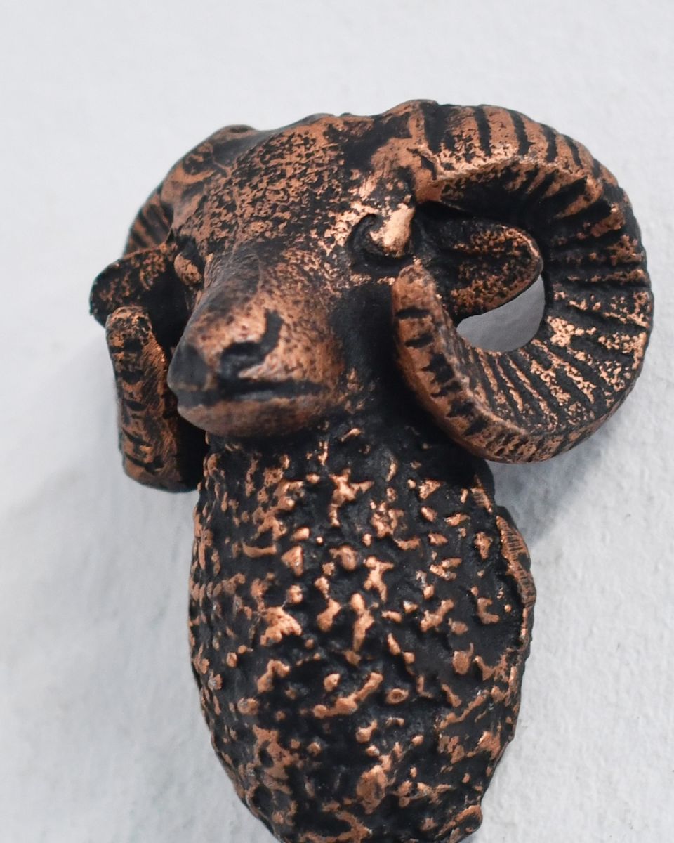 Close up of intricate ram head detailing on copper coat hook