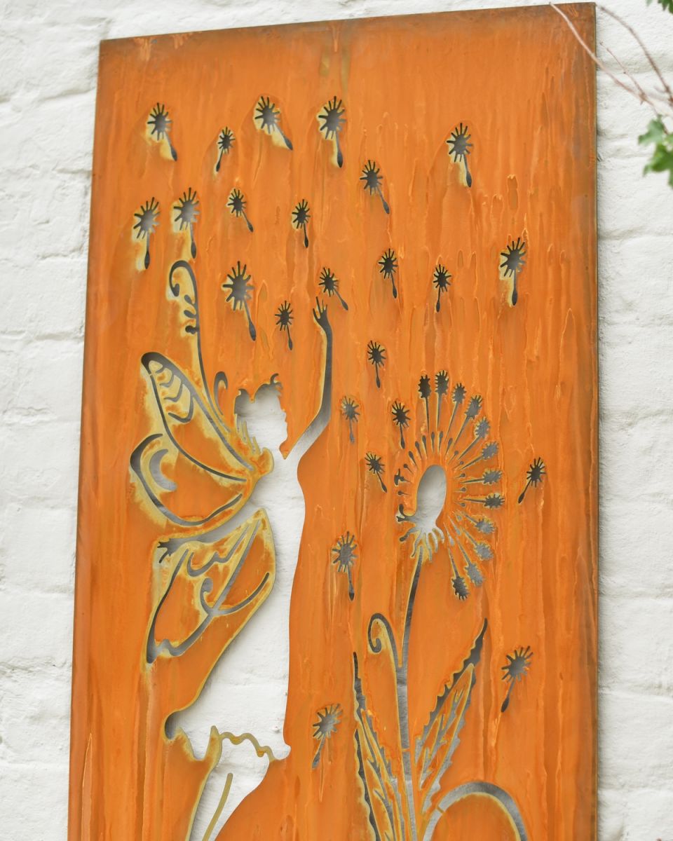 Close up of intricate fairy and dandelion cut out detail on rustic garden wall art Close up of intricate fairy and dandelion cut out detail on rustic garden wall art