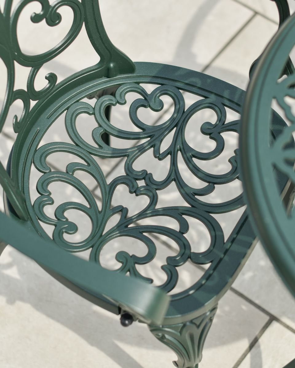 Close up of ornate seat detail in dark green garden two seater table and chairs set