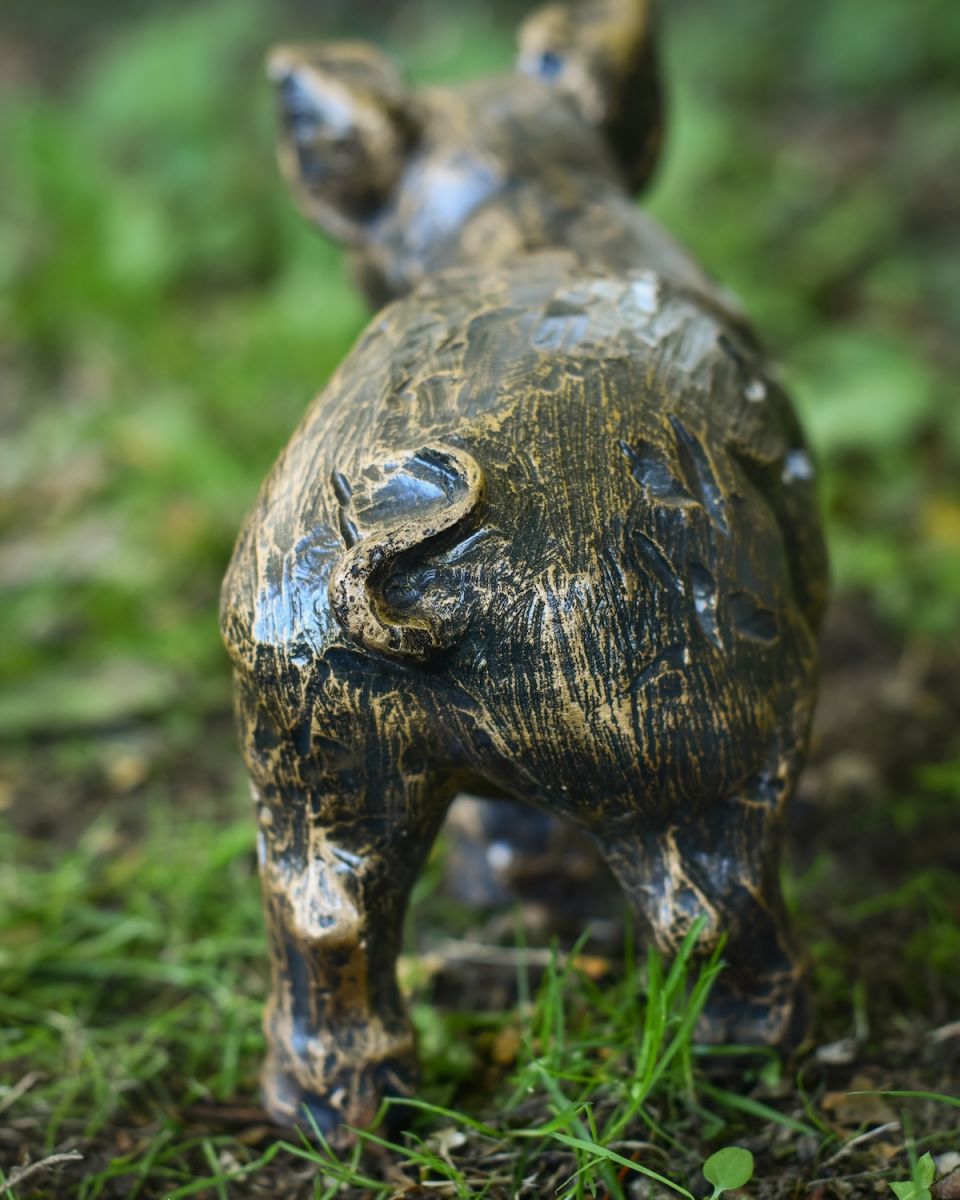 Close up of curly tail detail on piglet garden statue