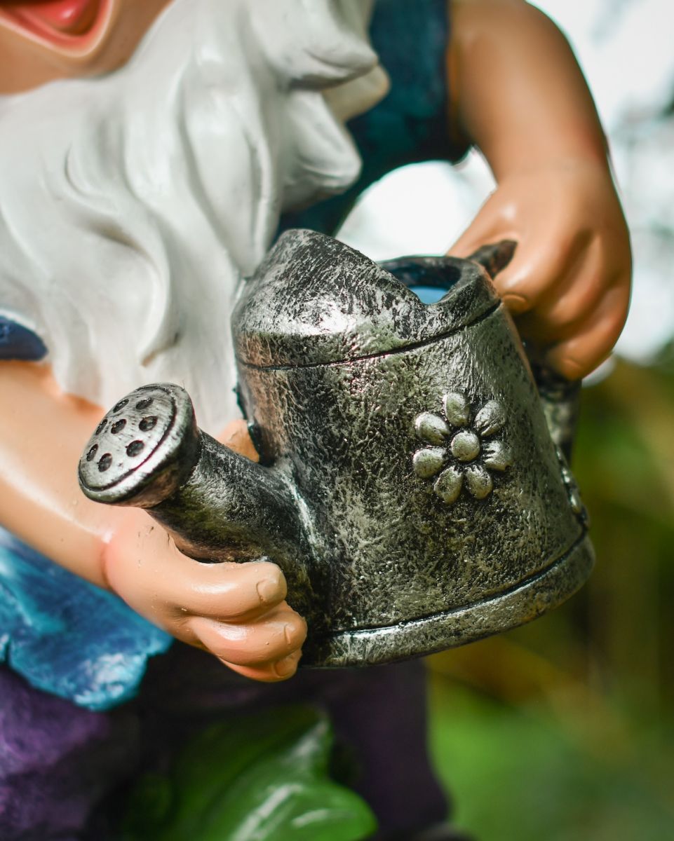 Close up of intricate watering can detail on colourful garden gnome