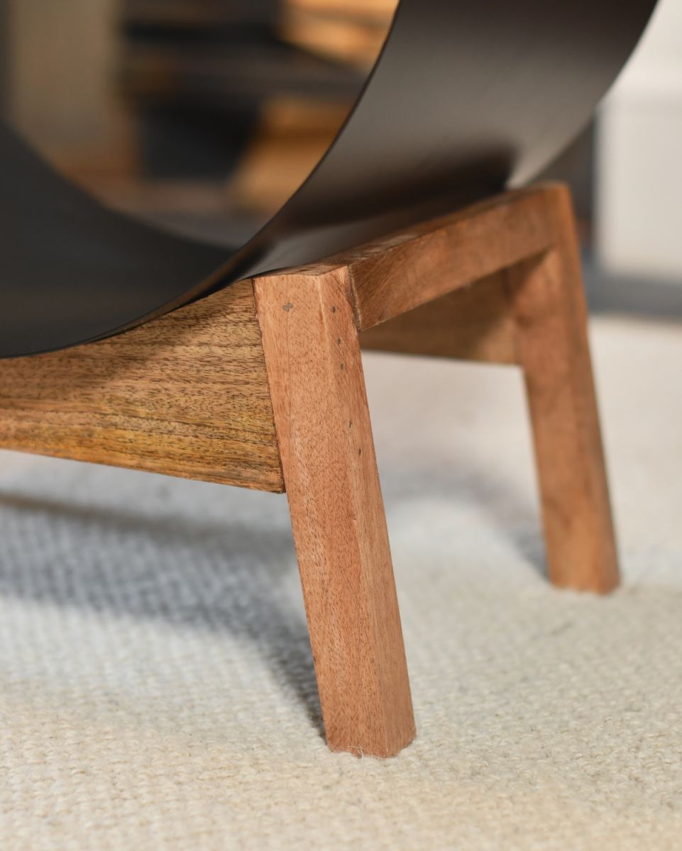 Close up of natural wooden leg detail on contemporary black and wood log holder