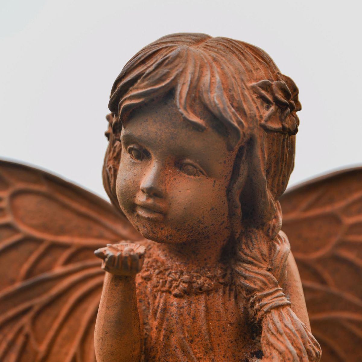 Close-Up of Rustic Cast Iron Fairy with Flower Sculpture Close-Up of Rustic Cast Iron Fairy with Flower Sculpture