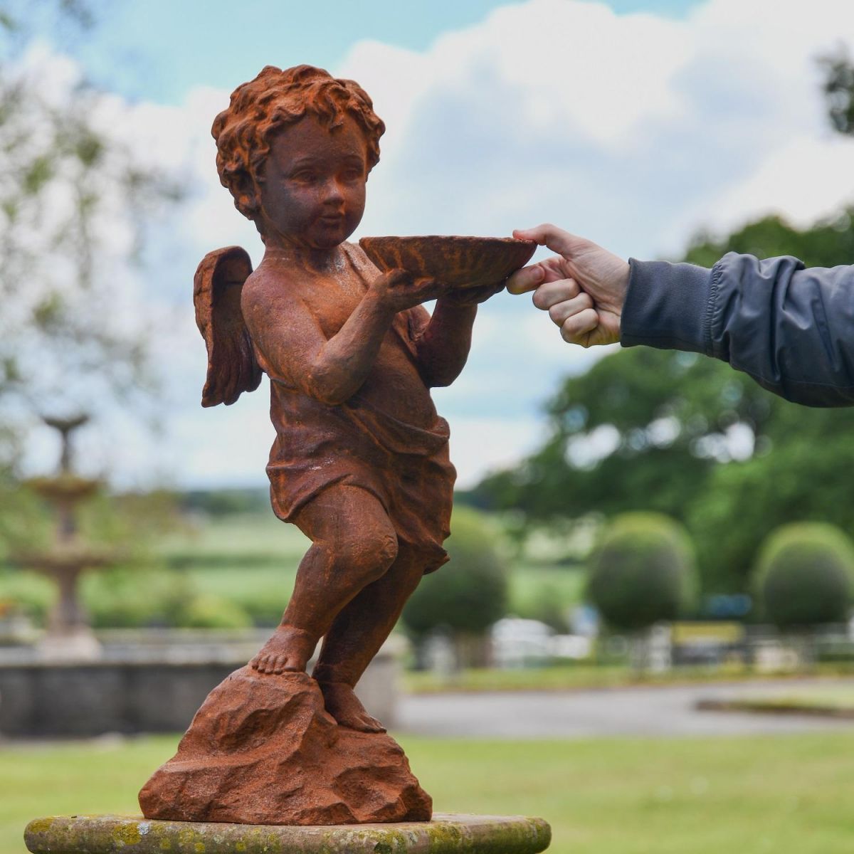 Rustic Cast Iron Winged Cherub with Bird Bath Sculpture with Hand for Scale  Rustic Cast Iron Winged Cherub with Bird Bath Sculpture with Hand for Scale