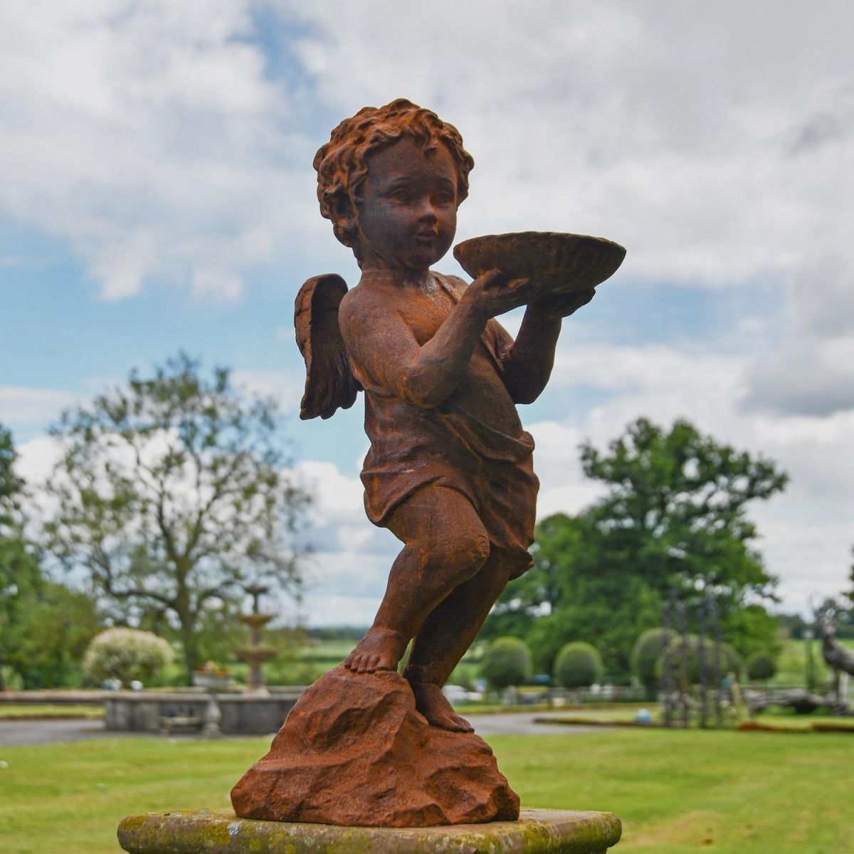 Rustic Cast Iron Winged Cherub with Bird Bath Sculpture in Garden  Rustic Cast Iron Winged Cherub with Bird Bath Sculpture in Garden