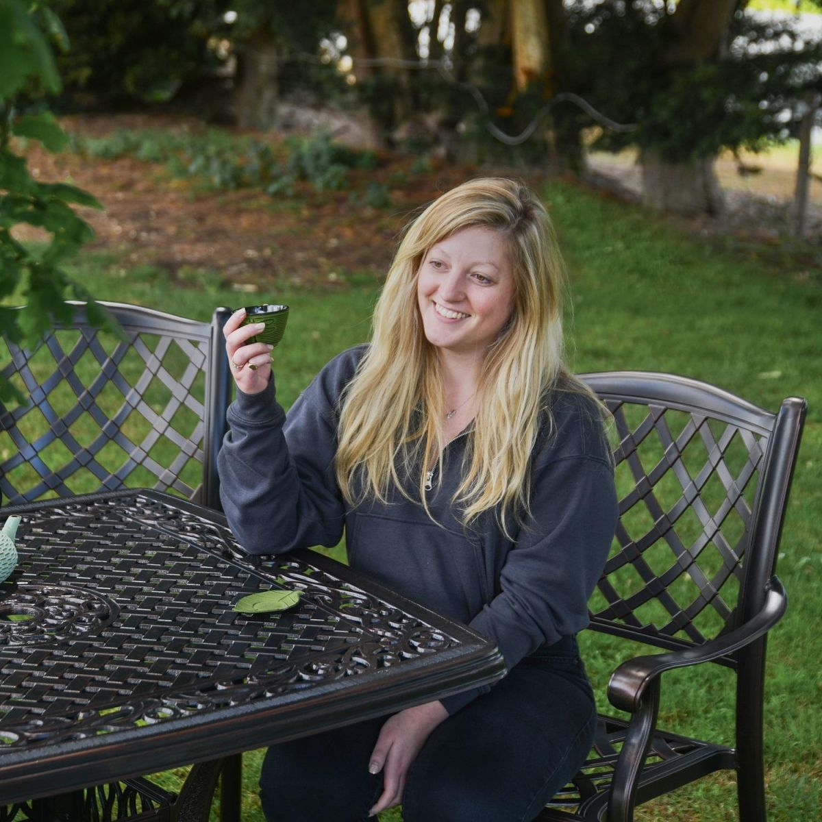 Female Sat at Antique Copper "Hawkstone" Garden Furniture Set 