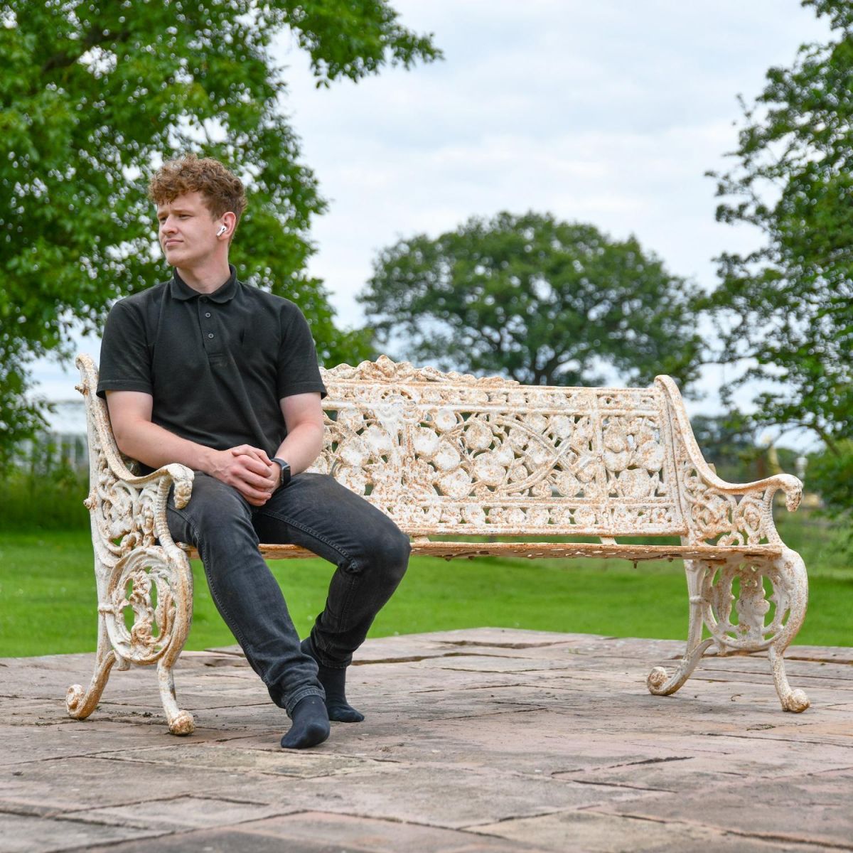 Male sat on Antique Cream Cast Iron Leaf Scroll Bench for Scale