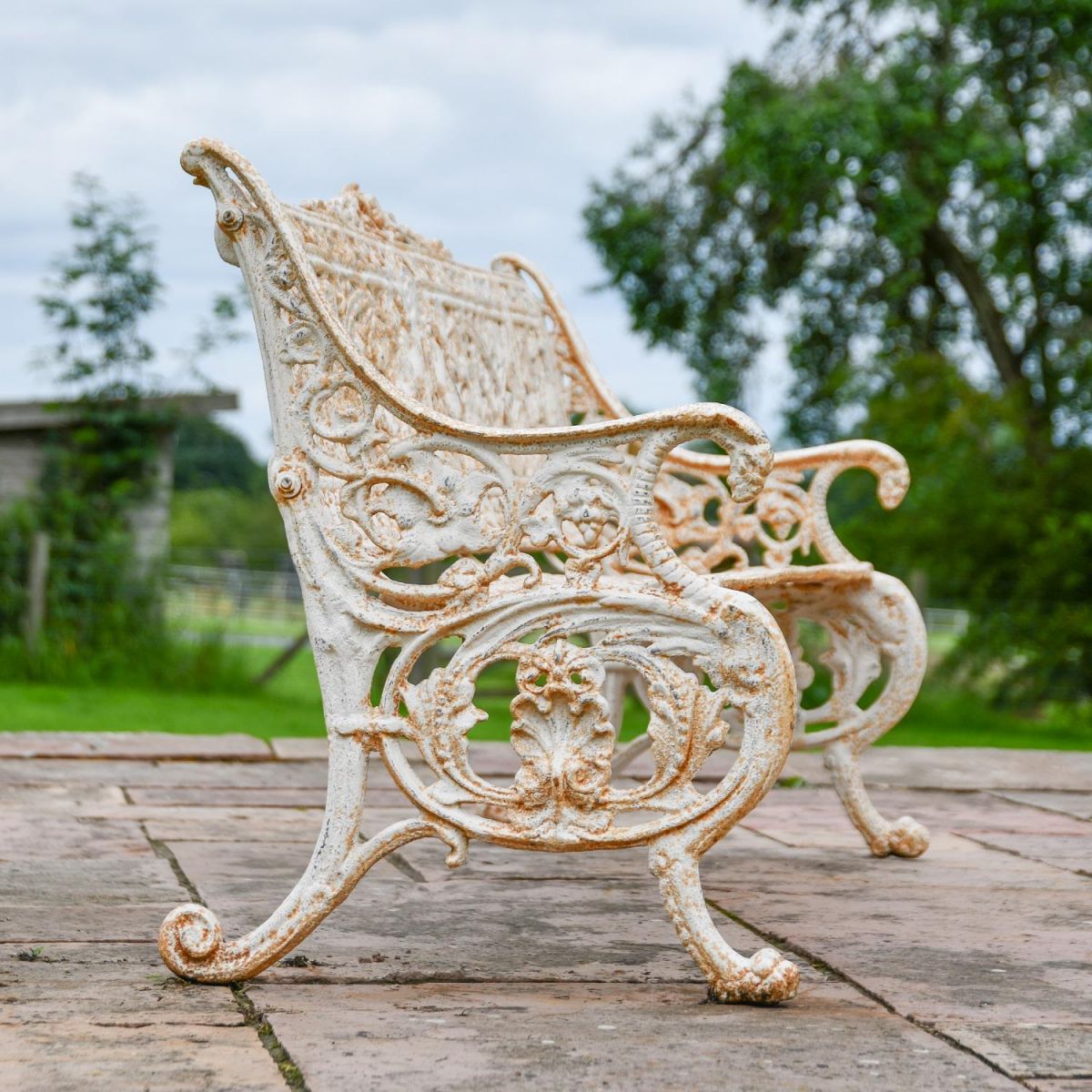 Side view of ornate scroll and leaf detailing on Antique Cream Bench