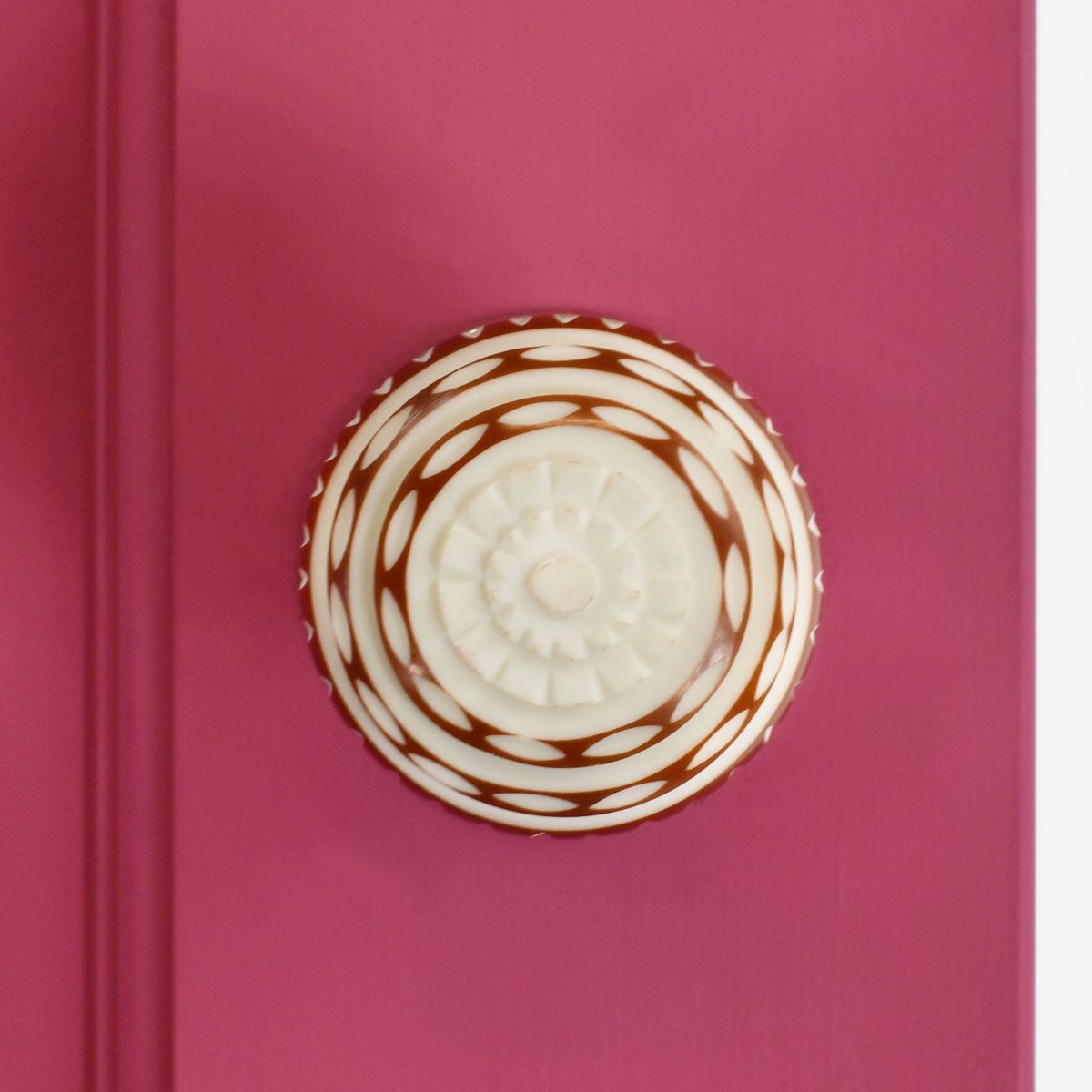 Red and white door knob on pink door