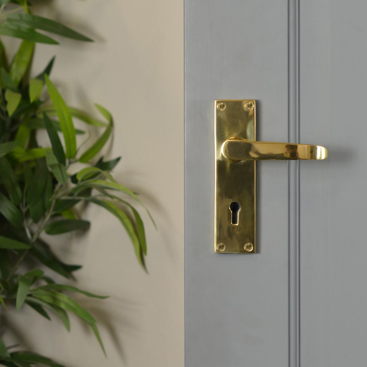 Polished Brass Lever Handle With Key Hole in Situ on Grey Door