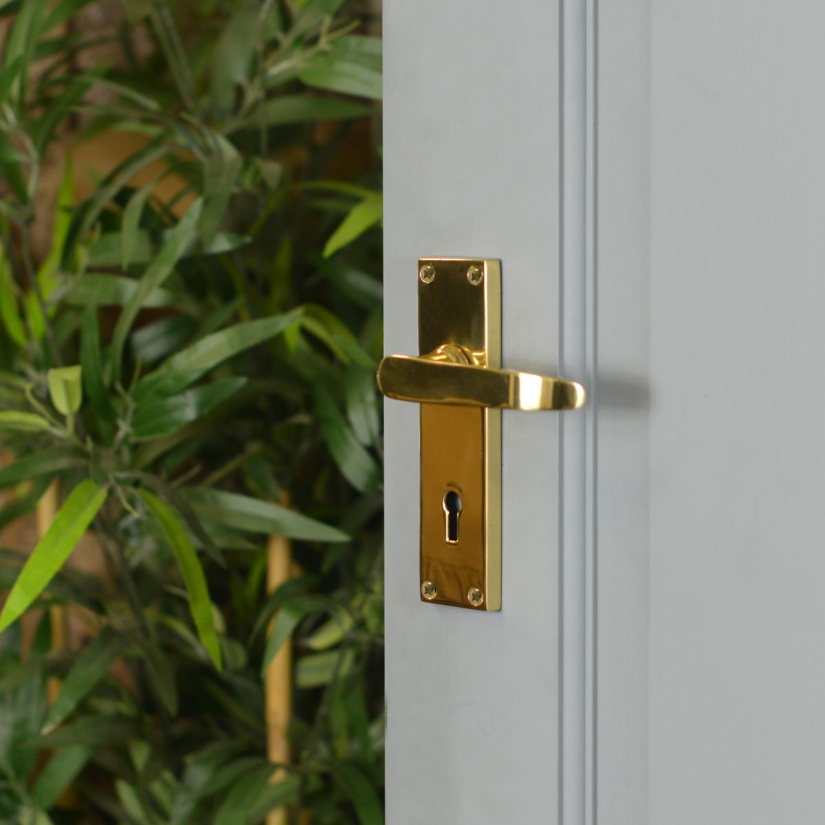 Polished Brass Lever Handle With Key Hole on Open Grey Door
