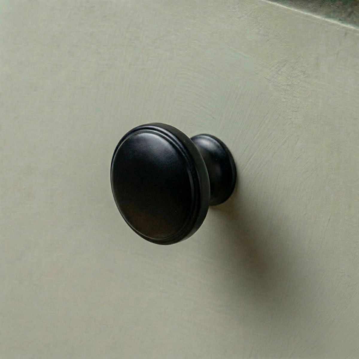 Digital Illustration of the 32mm Steel Powder Coated Cabinet Knob Mounted on a Green Cupboard Door