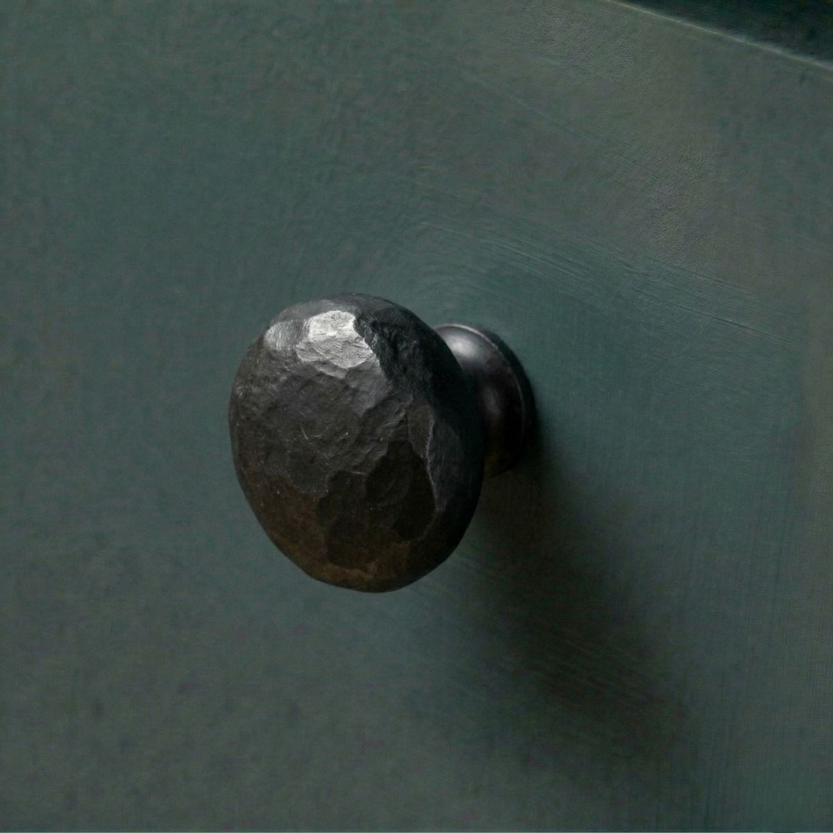 Digital Illustration of the 33mm Black Hammered Steel Cabinet Knob Mounted on a Blue Cupboard Door