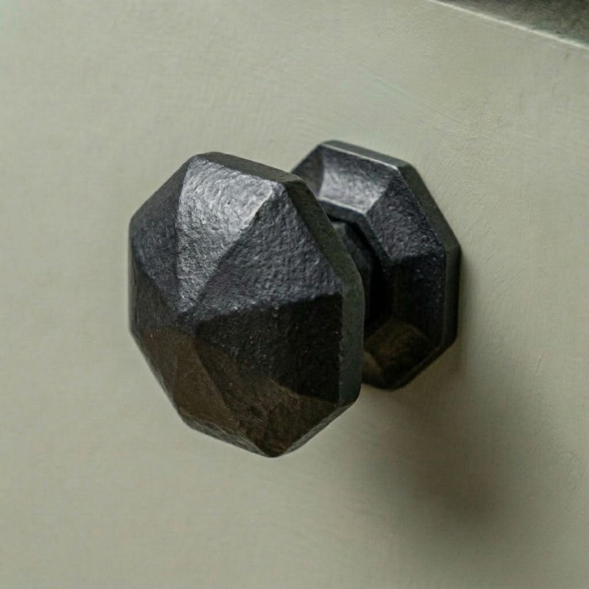 Digital Illustration of the 39mm Steel Beeswax Octagonal Cabinet Knob Mounted on a Sage Green Cupboard Door