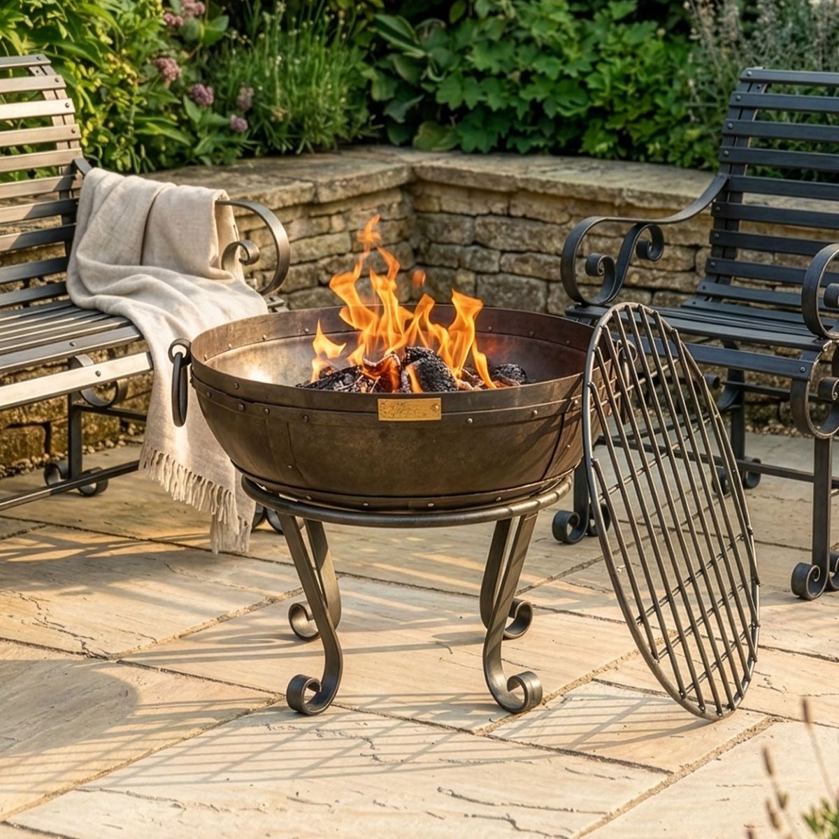 Digital Illustration of the 60cm Version of the Iron Kadai Bowl Fully Lit in Front of Rustic Garden Furniture