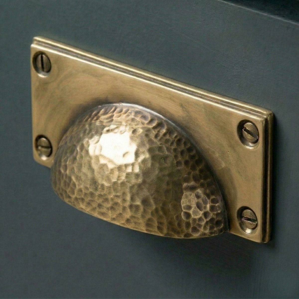 Digital Illustration of the Aged Brass Rectangular Drawer Pull with Curved Hammered Handle Mounted on a Blue Cupboard