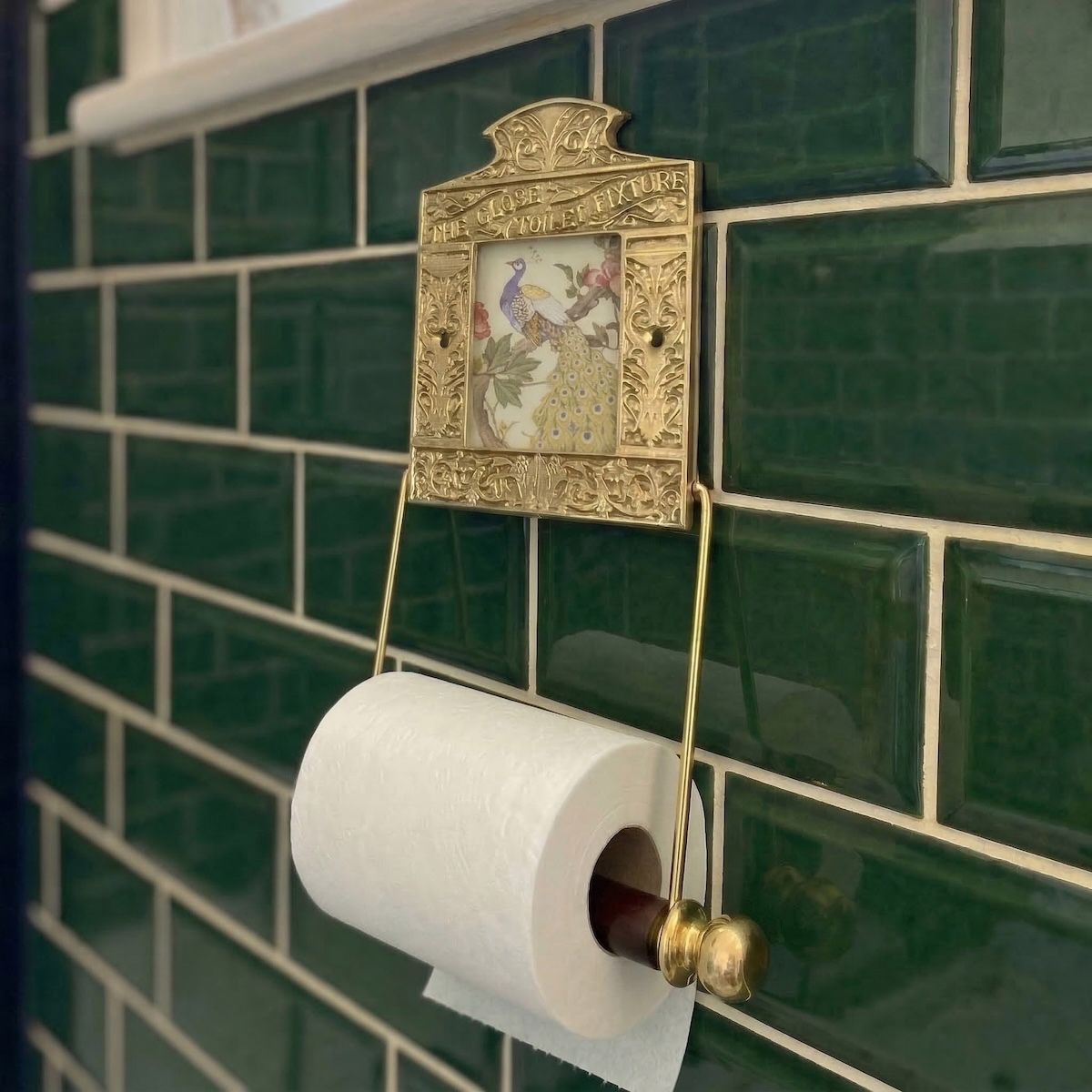 Digital Illustration of the Brass Version of the Globe Toilet Fixture Holding Toilet Roll Mounted on Green Bathroom Tiles