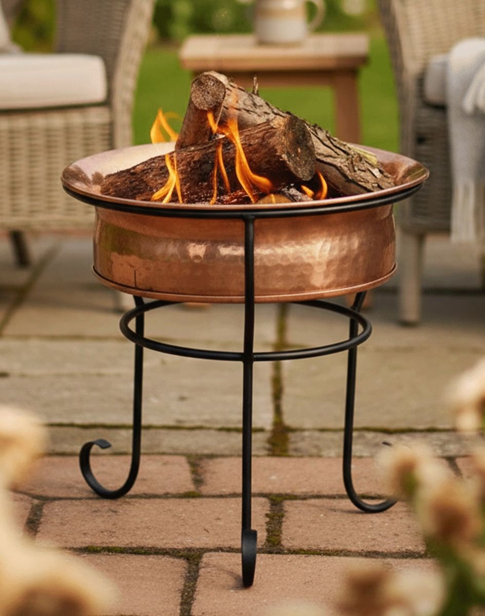 Digital Illustration of the Copper Marrakech Fire Pit with Lit Logs Positioned in Pit on a Brick Garden Patio