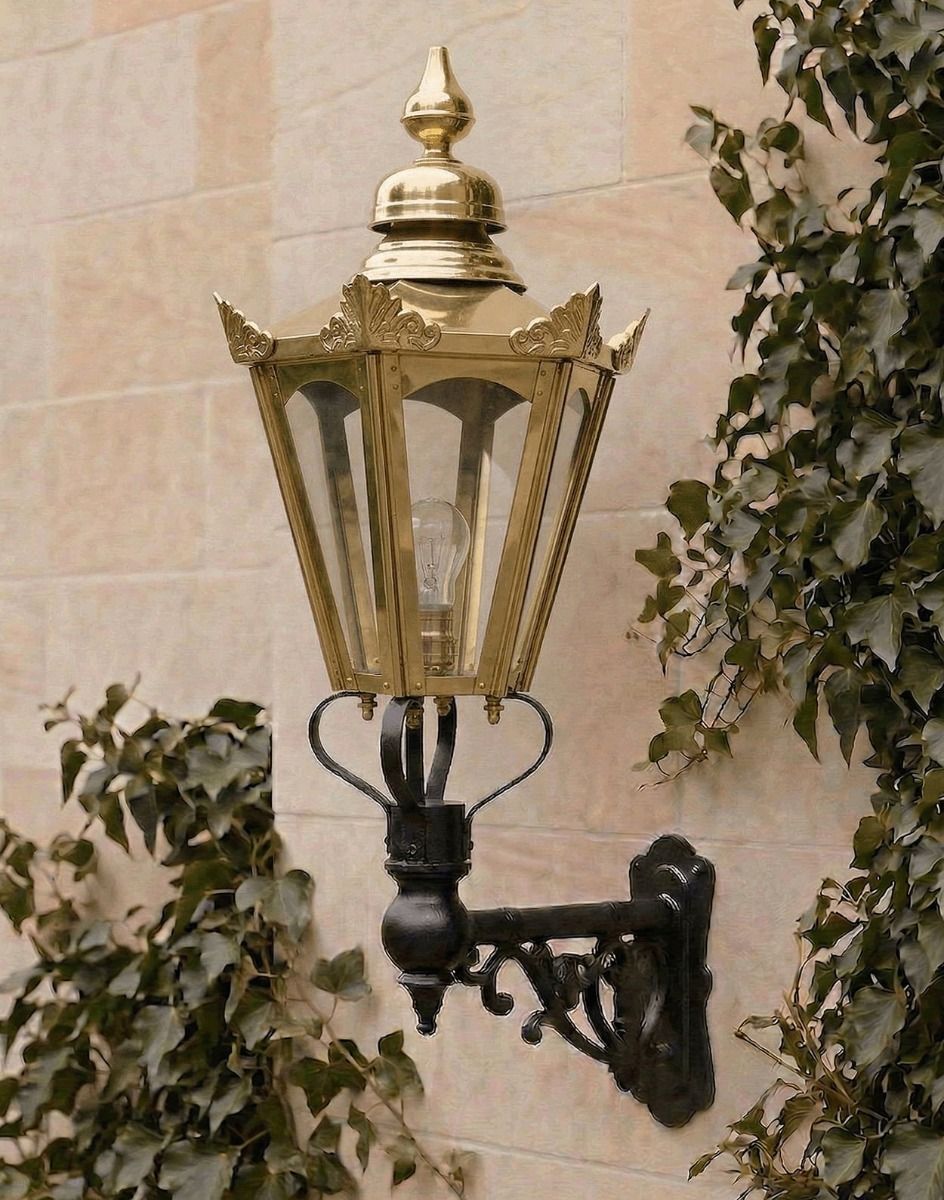Digital Illustration of the Medium Concordia Hexagonal Brass Lantern On a Capella Bracket Lit up at Night Mounted on a light Coloured Sandstone Brick Wall