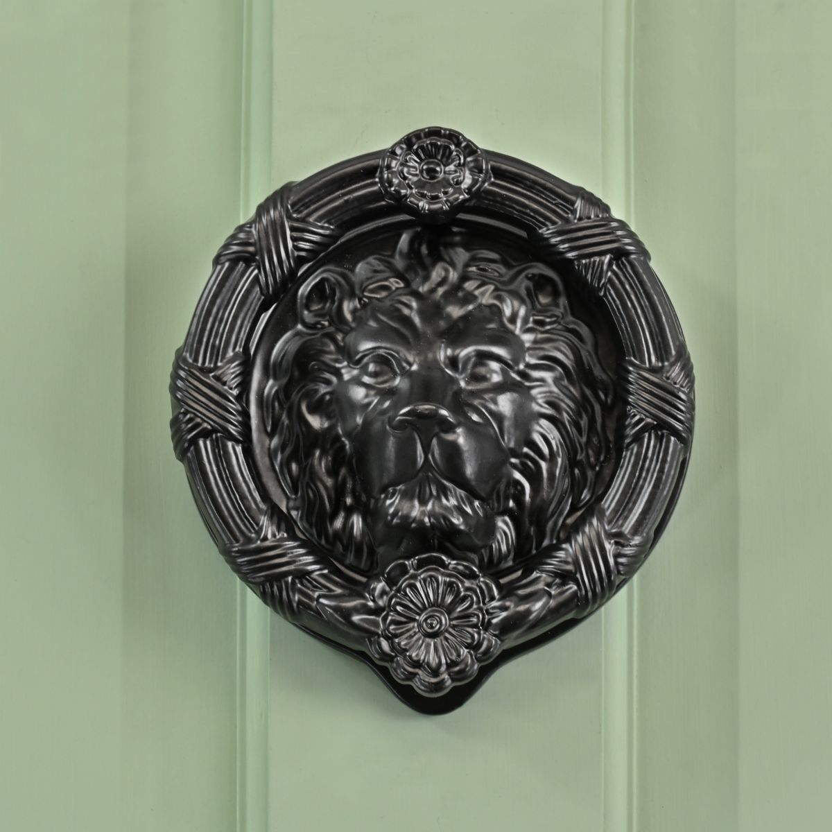 Traditional Sandringham black lion door knocker on pastel green door