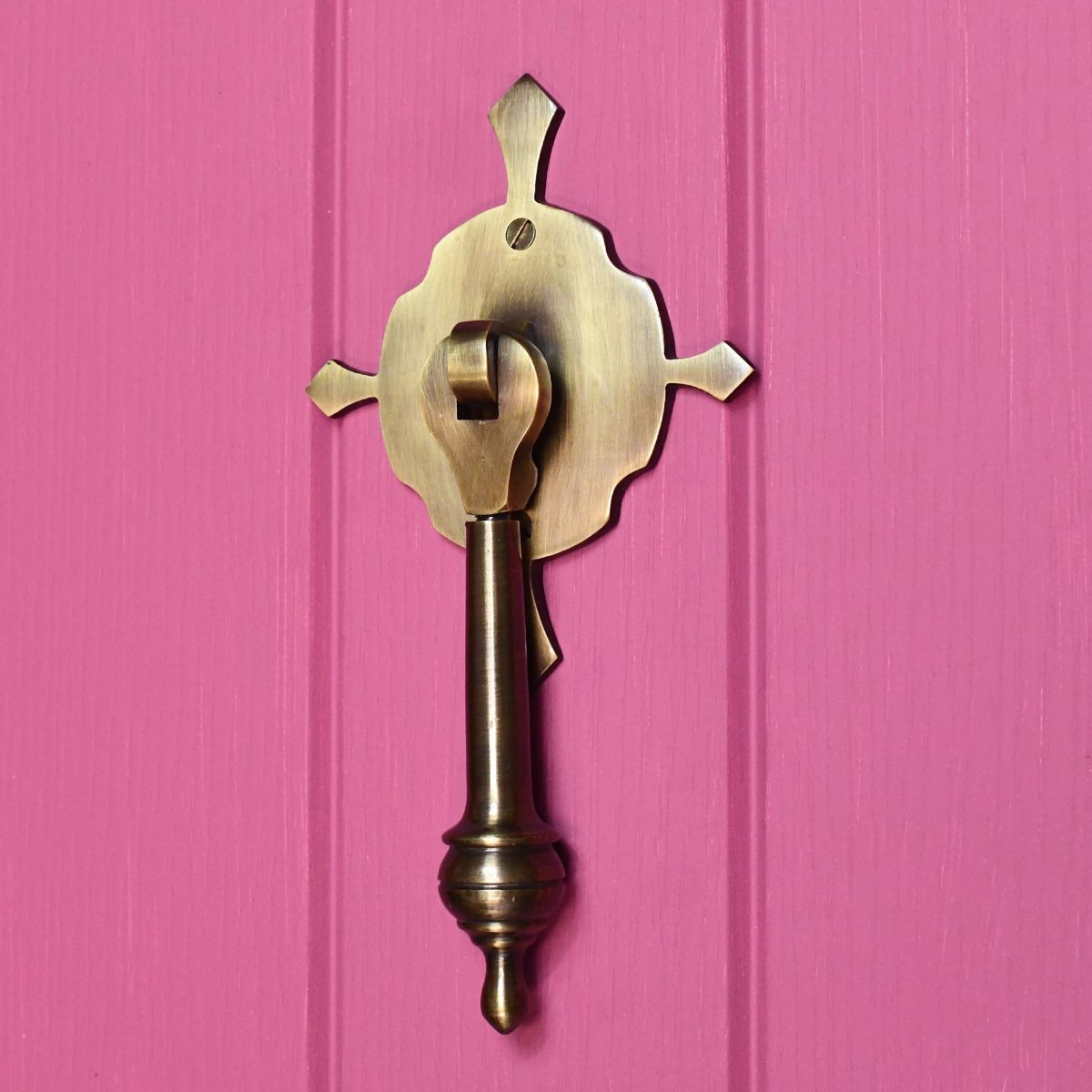 Antique Brass pendulum door knocker on pink door