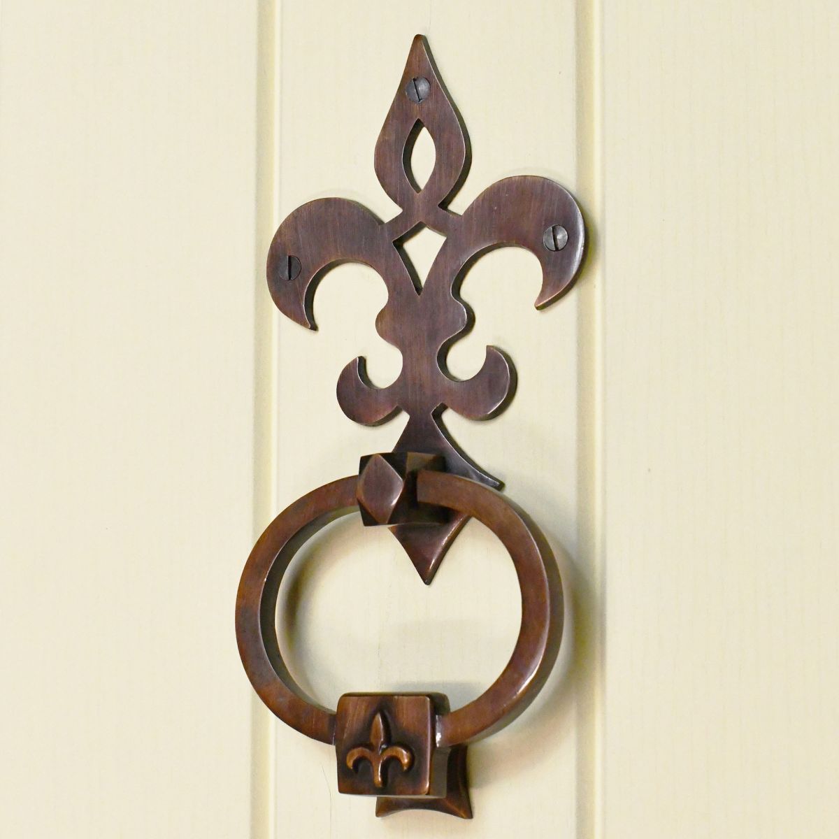 Fleur de lys design door knocker on cream door