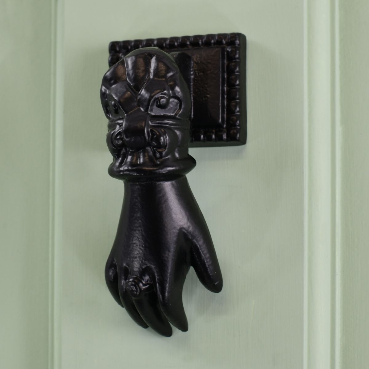 Black Hand door knocker on pale green door