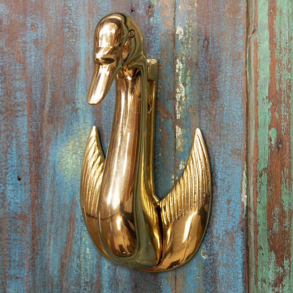 Brass swan knocker on weathered door