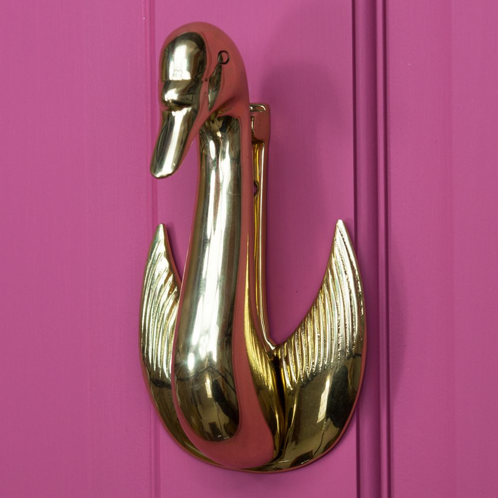 Brass Swan design door knocker mounted on pink door