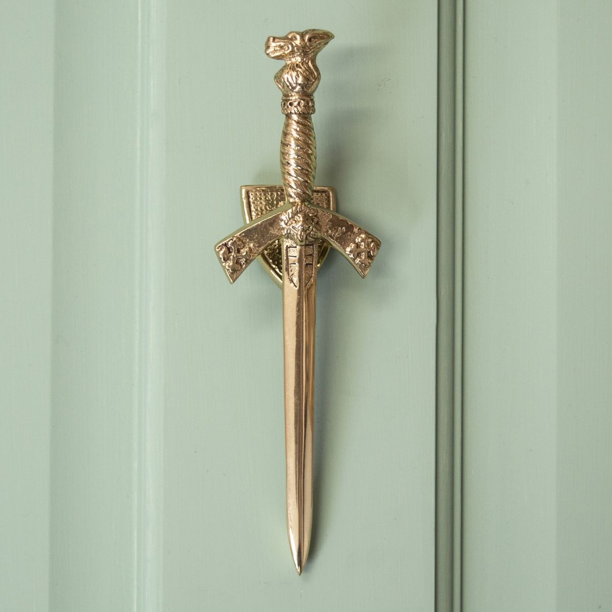 Polished Brass Sword Door Knocker on Pale Green Door